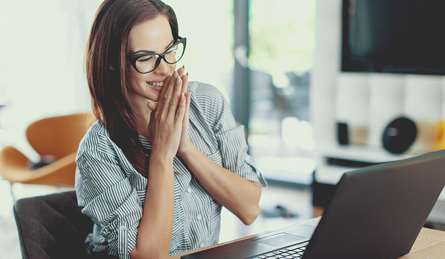 Woman sitting at laptop looking excited.