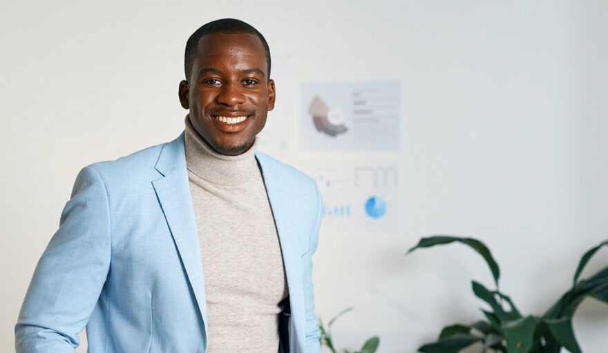 Athletic looking man standing in his office. Wearing a light blue blazer