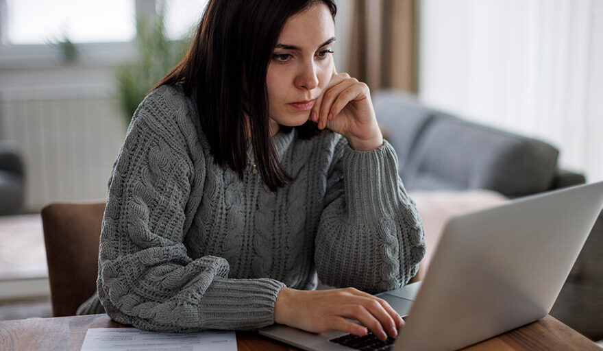 Woman on a laptap concentrating and looking serious.