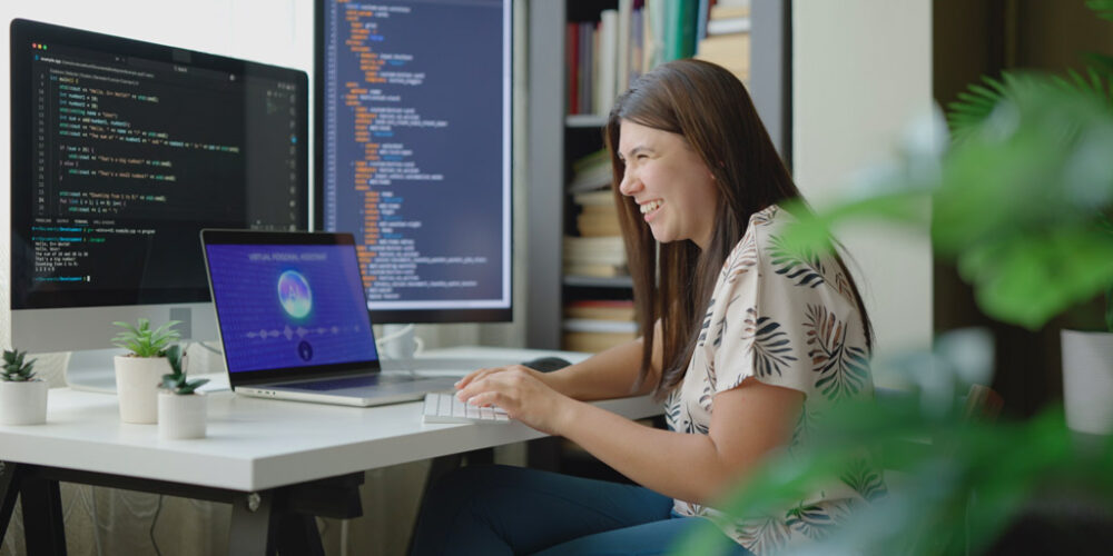 Smiling woman using AI on a computer in an office setting.