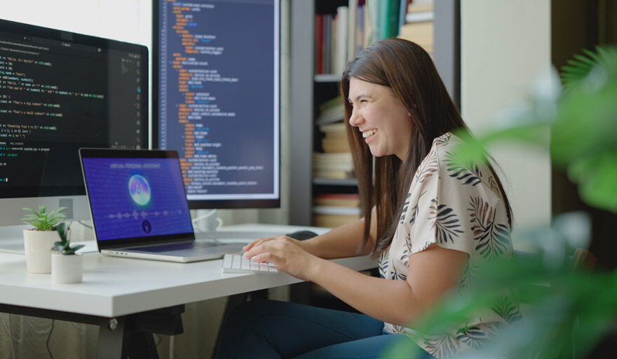 Smiling woman using AI on a computer in an office setting.