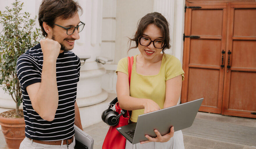 Woman smiling while showing a smiling man something on a laptop.