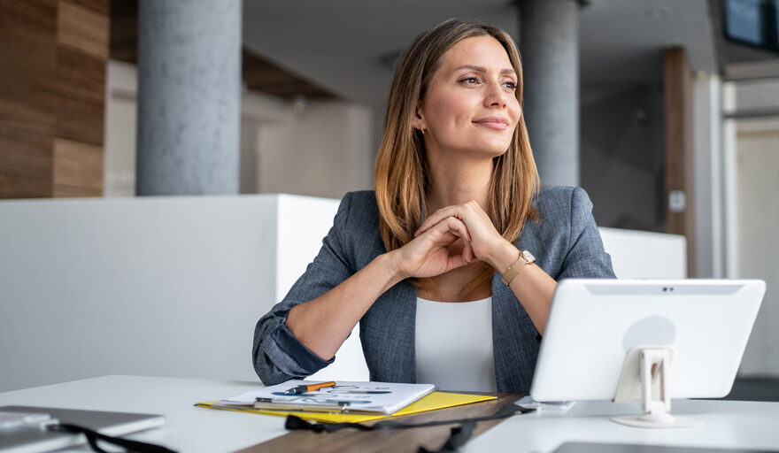 A professional woman sitting at her desk looking content